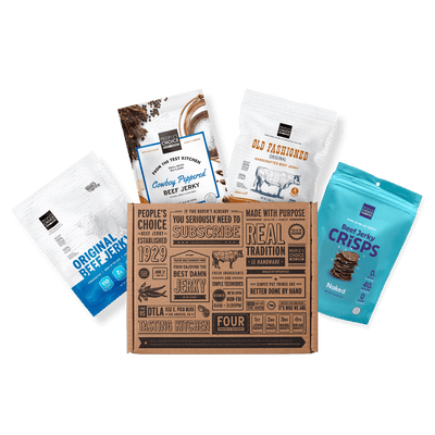 A curated snack box set featuring a central kraft cardboard subscription box surrounded by four branded snack pouches: Original Beef Jerky, Country-Raised Beef Jerky, Old Fashioned Chocolate Chip Cookie, and Beef Jerky Crisps.