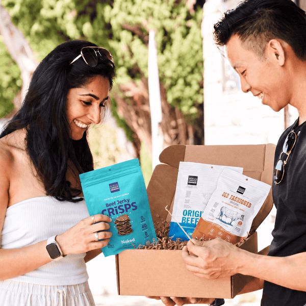 Two people holding a simple and savory jerky box. 