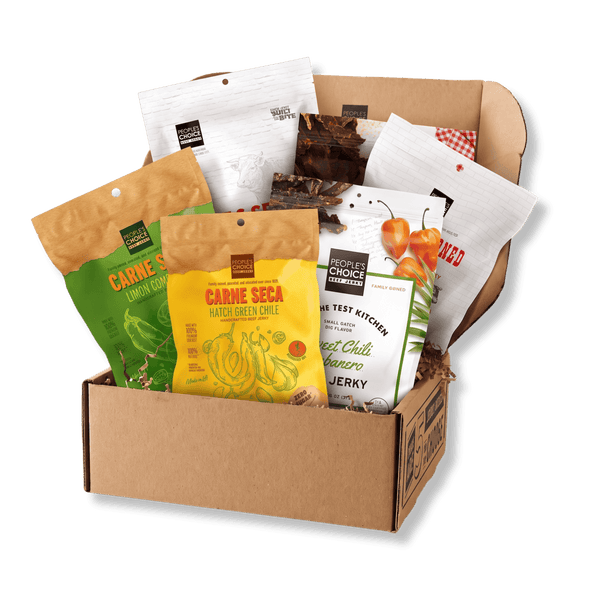 A cardboard gift box filled with assorted packaged snacks and jerky from Choice Choice Restaurants and Carne Seca, photographed on a clean white background.