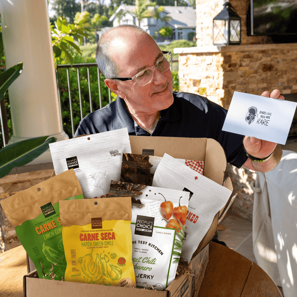 Man opening a jerky box as a gift and holding up a card. 