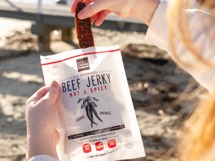 Photo of persons hand holding a bag of beef jerky